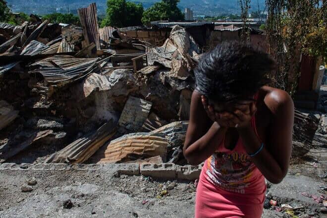 A woman cries outside her house after armed gangs set it on fire in the Post Marchand neighborhood of Port-au-Prince on Dec. 17, 2024. Photo by Clarens Siffroy/AFP via Getty Images.