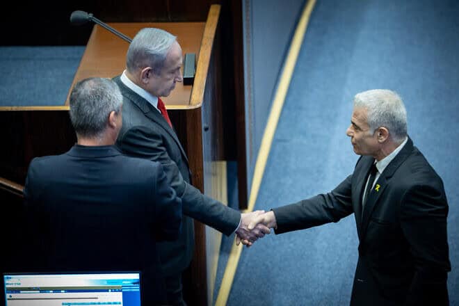 Israeli Prime Minister Benjamin Netanyahu shake hands with Opposition Leader Yair Lapid at a plenum session for Israeli Knesset's 75th birthday, in the assembly hall of the Knesset, the Israeli parliament in Jerusalem, Israel on Jan, 24, 2024. Photo by Yonatan Sindel/Flash90.