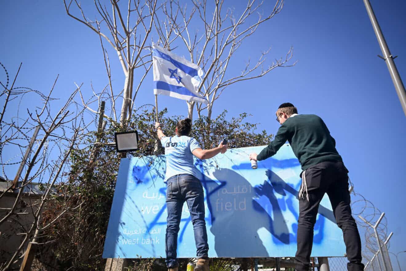 B'tsalmo CEO Shai Glick (right) and a fellow activist paint over the UNRWA sign at the agency's former office in Jerusalem's Ma'alot Dafna neighborhood on Jan. 30, 2025. Photo by Aron Leib Abrams/Flash90.