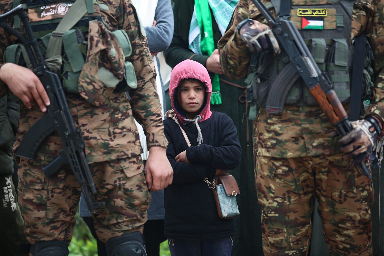 Hamas terrorists in the Gaza Strip, along with children present, observe a propaganda ceremony during which Israeli hostages who were taken during the terrorist attacks in southern Israel on Oct. 7, 2023 are turned over to the Red Cross, Feb. 22, 2025. Credit: Ali Hassan/Flash90.