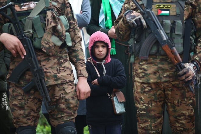 Hamas terrorists in the Gaza Strip, along with children present, observe a propaganda ceremony during which Israeli hostages who were taken during the terrorist attacks in southern Israel on Oct. 7, 2023 are turned over to the Red Cross, Feb. 22, 2025. Credit: Ali Hassan/Flash90.
