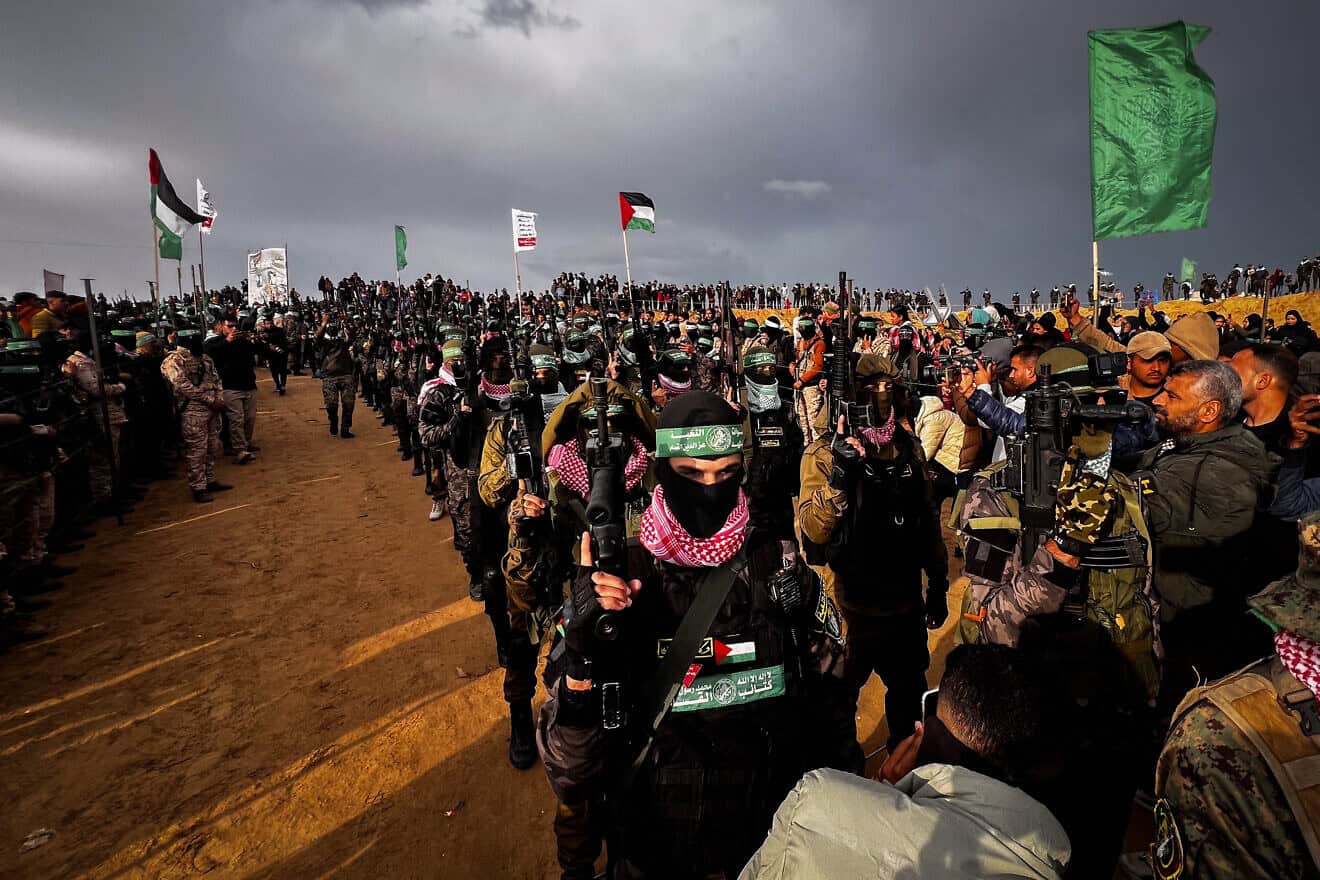 Members of Al-Qassam Brigades, the Hamas “military“ wing, stand guard while Palestinians wait to hand over the bodies of four Israeli hostages to the Red Cross in Khan Yunis, the southern Gaza Strip, Feb. 20, 2025. Photo by Saeed Mohammed/Flash90.