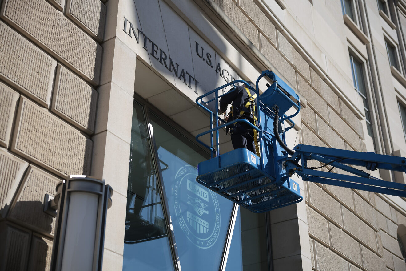 A worker removes the U.S. Agency for International Development sign on its headquarters on Feb. 7, 2025. Photo by Kayla Bartkowski/Getty Images.