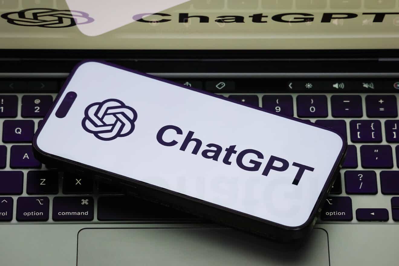 A close-up of a smartphone displaying the ChatGPT logo on a white screen, with the same ChatGPT logo shown on a laptop screen on February 19, 2025 in Chongqing, China. Photo by Cheng Xin/Getty Images.
