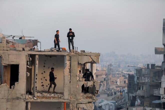 Men stand on a damaged rooftop overlooking an Iftar break-fast gathering in Beit Lahia, northern Gaza, on March 15, 2025. Photo by Saeed Jaras/Middle East Images/AFP via Getty Images.
