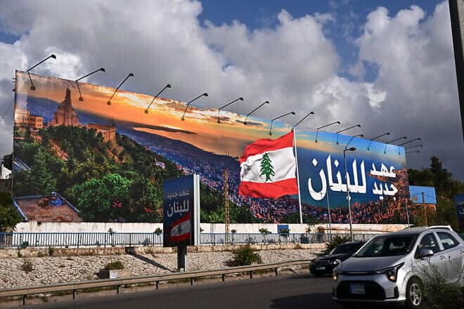 Commuters drive past a newly installed billboard bearing the image of a Lebanese flag and a statement that reads in Arabic "Lebanon a new era," replacing a Hezbollah billboard, on the road leading to Beirut's Rafic Hariri International Airport on April 10, 2025. Photo by Joseph Eid/AFP via Getty Images.
