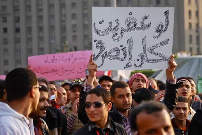 Crowd of protesters hold signs during the 2011 Egyptian revolution. Credit: Mariam Soliman via Wikimedia Commons.