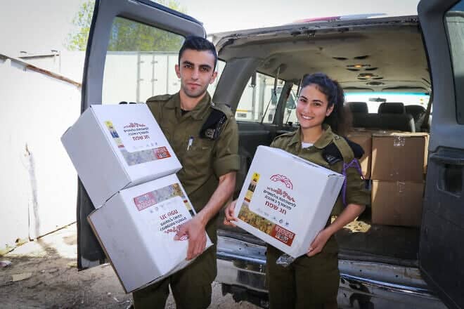 Representatives of IDF units hold food products donated by residents in the surrounding communities in Gush Etzion that will be giving away later to families of IDF soldiers, in Gush Etzion, in Judea and Samaria, on March 28, 2017, ahead of the Jewish holiday of Passover. Photo by Gershon Elinson/Flash90.