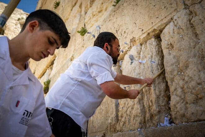 Workers remove handwritten notes placed between the ancient stones of the Western Wall in the Old City of Jerusalem, April 2, 2025. Photo by Yonatan Sindel/Flash90.