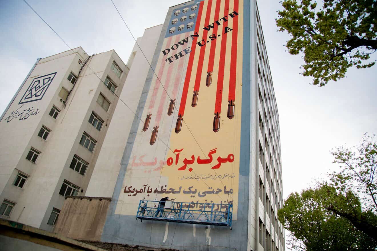 A man repaints a famous mural that depicts the U.S. flag with bombs and skulls and reads "Down with the U.S.A." in central Tehran on April 1, 2025. Photo by A O/ Middle East Images/AFP via Getty Images.