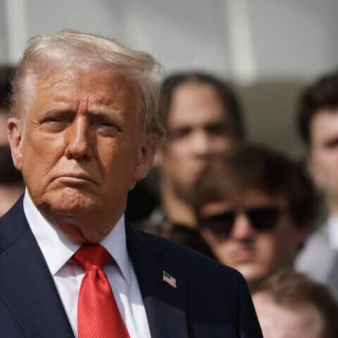 Президент США Дональд Трамп слушает выступление главного тренера Университета штата Огайо Райана Дэя, который приветствует чемпионов страны по студенческому американскому футболу 2025 года из Университета штата Огайо в Белом доме во время церемонии на южной лужайке 14 апреля 2025 года в Вашингтоне, округ Колумбия. Фотография Уина Макнами/Getty Images.
