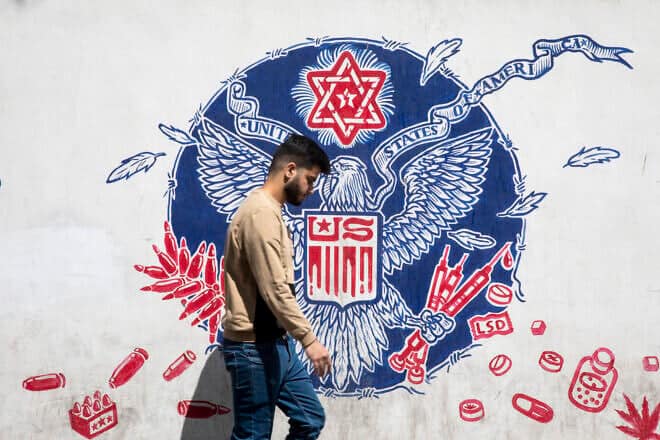 A mural depicting a mock version of the Great Seal of the United States, with the eagle holding syringes and ammunition cartridges in its talons and a Star of David is seen painted on the outer walls of the former US embassy in Tehran, colloquially-referred to as the Spy Den, on April 19, 2025 in Tehran, Iran. Photo by Majid Saeedi/Getty Images.