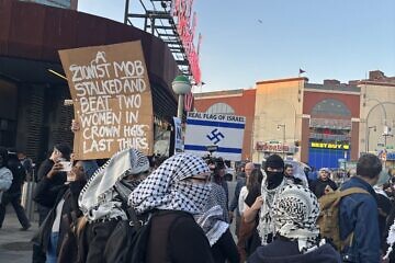 An anti-Israel protester holds a sign stating “a Zionist mob stalked and beat two women in Crown Heights last Thursday” at the Barclays Center in downtown Brooklyn, N.Y., before attempting to march toward 770 Eastern Parkway. April 28, 2025. Photo by Vita Fellig.