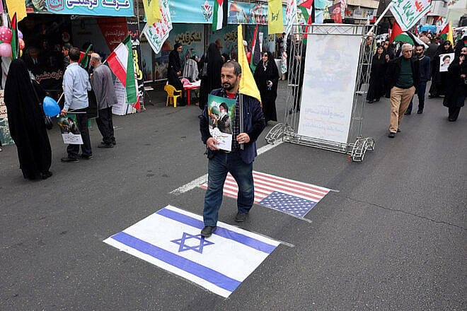 A man steps on Israeli and U.S. flags at a rally marking Al-Quds Day in Tehran on March 28, 2025. Photo by AFP via Getty Images.