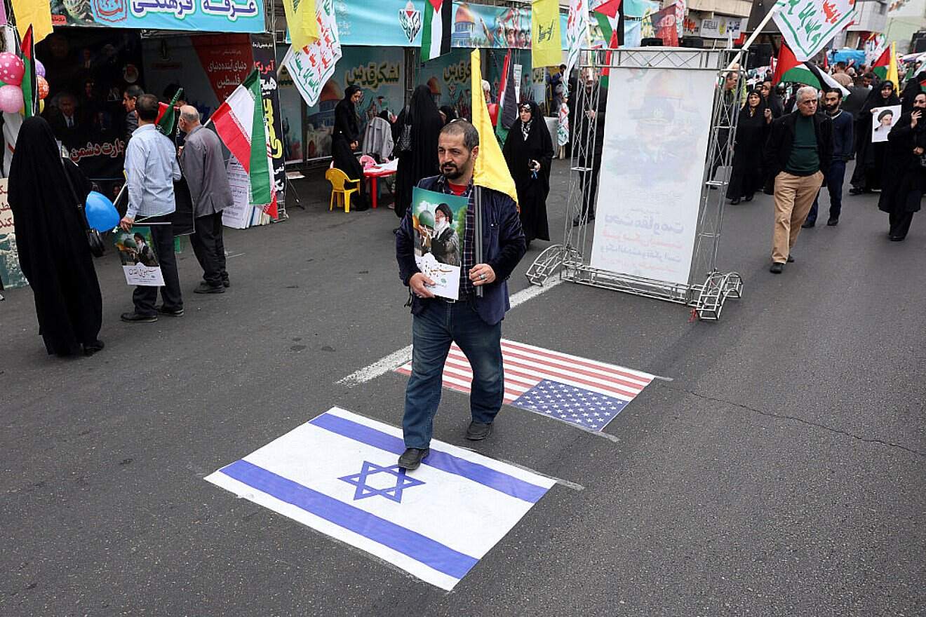 A man steps on Israeli and U.S. flags at a rally marking Al-Quds Day in Tehran on March 28, 2025. Photo by AFP via Getty Images.