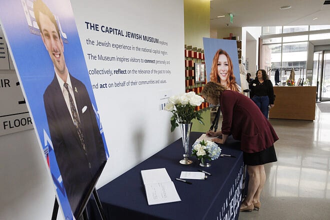 Beatrice Gurwitz, executive director of the Capital Jewish Museum, writes a note in a memorial book for Yaron Lischinsky and Sarah Milgrim, which will be given to their families, at the museum reopening in Washington, D.C., on May 29, 2025. Credit: Jim Bourg/Capital Jewish Museum.