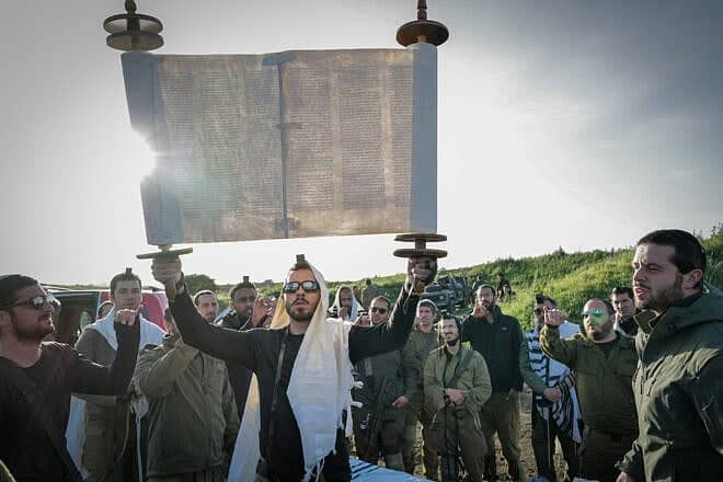 Israel Defense Forces Reserve soldiers and Orthodox Jews take part in prayer and the weekly reading of a Torah before a military exercise in the Golan Heights on April 1, 2024. Photo by Michael Giladi/Flash90.