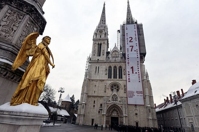 A banner states "Day of Remembrance for the Victims of the Holocaust" in Croatian and Hebrew on Zagreb's cathedral ahead of the International Holocaust Remembrance Day, Jan. 24, 2019. Photo by Denis Lovrovic/AFP via Getty Images.