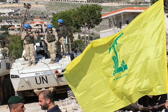 A resident of the Southern Lebanese village of Yaroun lifts a Hezbollah flag while gathering with others at the entrance of the town where soldiers of the Lebanese army and UNIFIL have deployed to prevent people from returning as Israeli forces remain in the area on January 28, 2025. Photo by Mahmoud Zayyat/AFP via Getty Images.