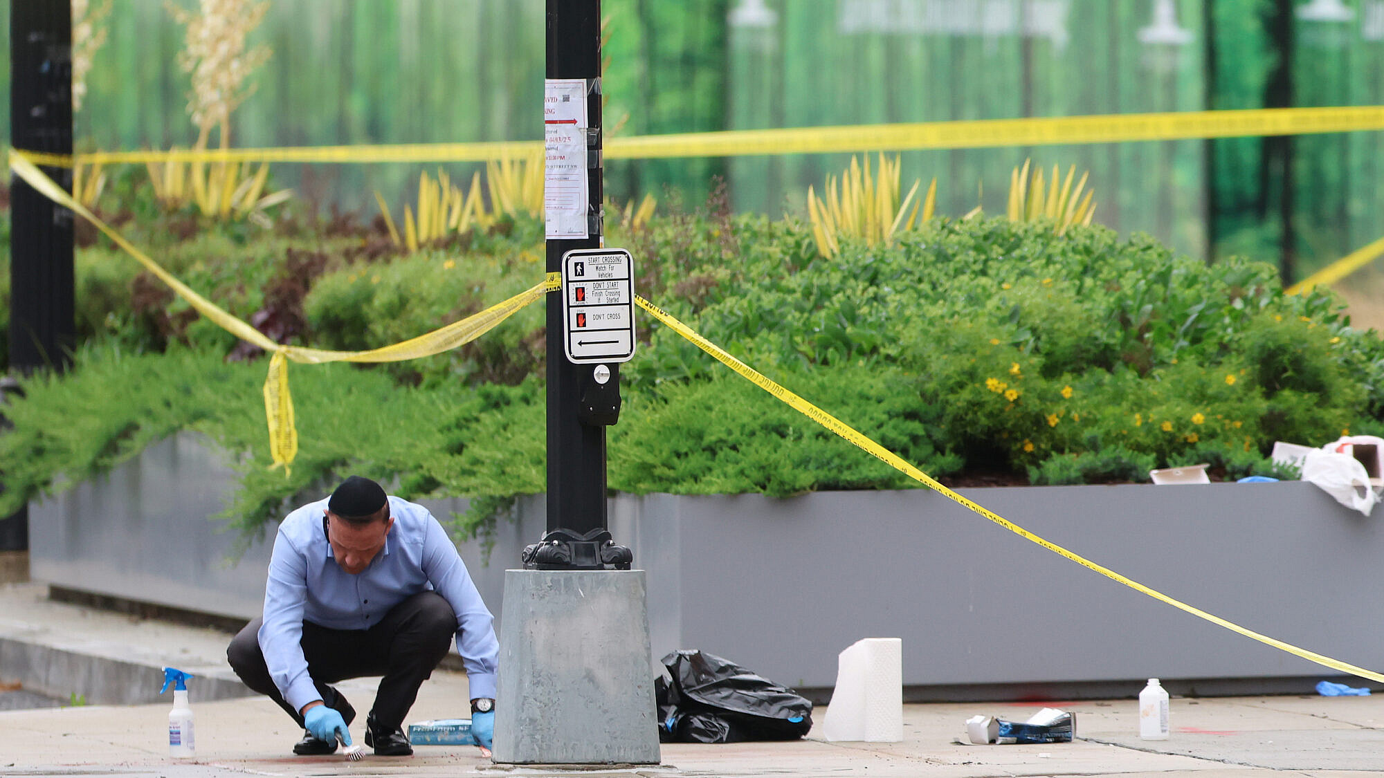 An Orthodox volunteer collects blood and other bodily remains off the sidewalk at the shooting location outside of the Capital Jewish Museum on May 22, 2025. Credit: Tasos Katopodis/Getty Images.