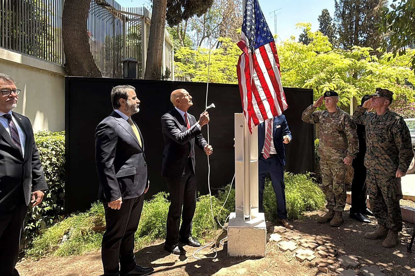 Syrian Foreign Minister Assaad al-Shibani (second left) looks on as U.S. Special Envoy for Syria Thomas Barrack raises the flag of the United States at the American ambassador's residence in Damascus on May 29, 2025. Photo by Rami Al Sayed/AFP via Getty Images.