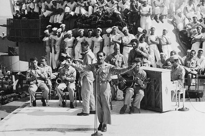 Irving Berlin performs aboard the “USS Arkansas” on July 25, 1944. Credit: U.S. Government Press Office via Wikimedia Commons.