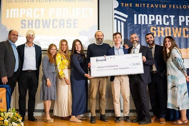 Gap-year students celebrate the culmination of their program in Israel at a ceremony held at Hebrew University’s Rothberg International School in Jerusalem. As part of the proceedings, Ben Goodman of New York holds a check for $5,000 for his winning project, Chaverut, May 27, 2025. Credit: Chaim H Photography.