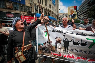 Palestinian protesters march during a rally marking the anniversary of the 
