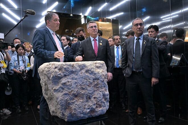 Israeli Foreign Minister Gideon Sa'ar (c) stands behind a stone on display that was part of a fortified tower built by the Hasmoneans in Jerusalem over 2,000 years ago, at the Israel Pavilion at Expo 2025 in Osaka, Japan, May 15, 2025. Credit: Shlomi Amsalem/MFA.