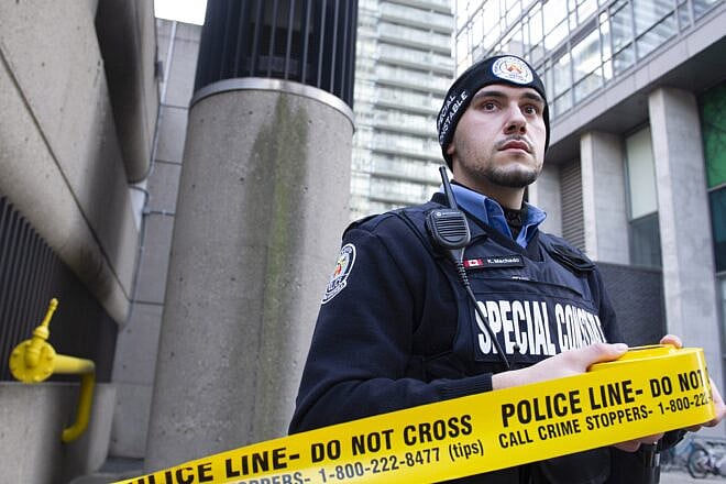 A special constable unrolls police tape. Credit: Kevin Masterman/Toronto Police Service.
