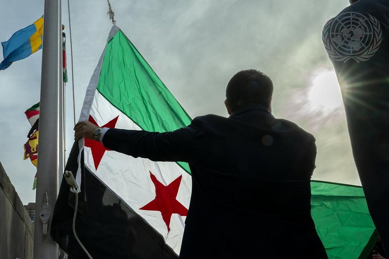 Asaad Al-Shaibani, minister of foreign affairs and expatriates of the Syrian Arab Republic, raises the new flag of Syrian Arab Republic during a flag-raising event held at U.N. Headquarters in New York, April 25, 2025. Credit: Mark Garten/U.N. Photo.