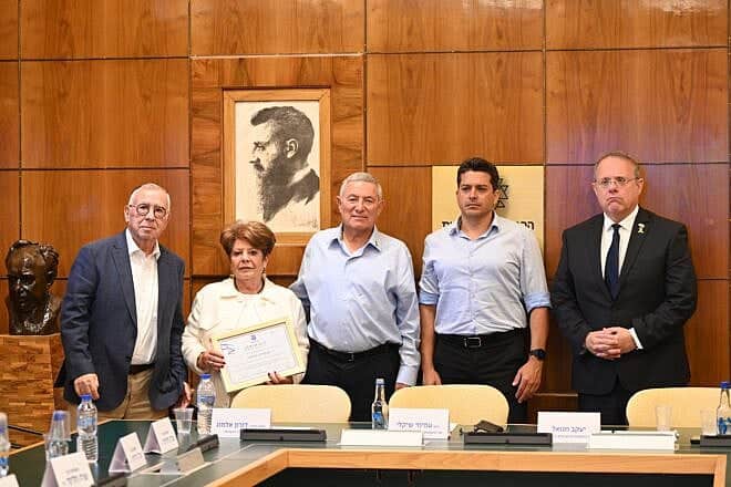 Jewish Agency chairmnan Doron Almog (center), flanked by Diaspora and Combating Antisemitism Minister Amichai Chikli (center-right) and World Zionist Organization chairman Yaakov Hagoel (far right), presents a certificate in memory of Dr. Joseph Wybran to his widow, Emmy Wybran-Sosnovski (center-left) and lifelong friend Jacques Heller at the Jewish Agency headquarters in Jerusalem. Photo by Yuval Yosef.