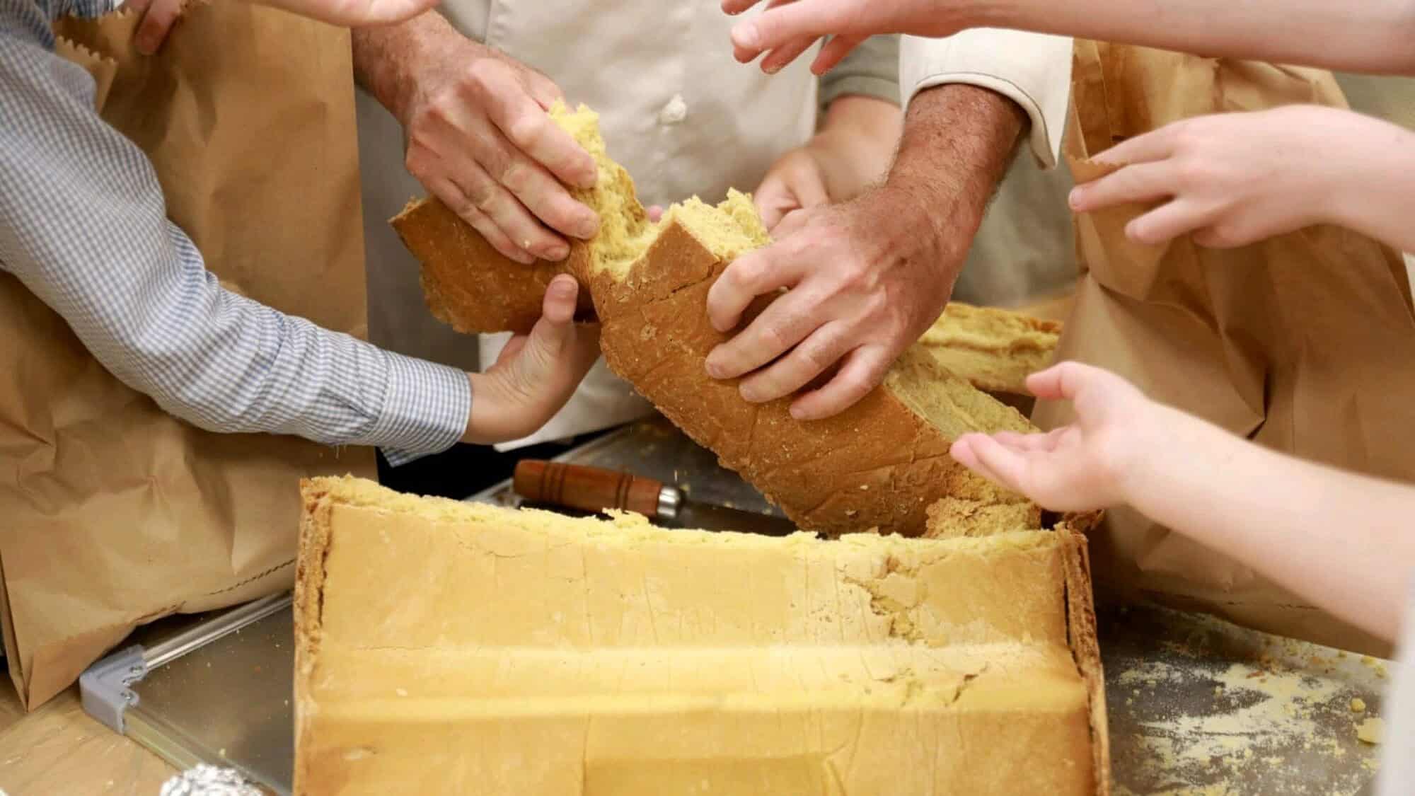 Baker Eliezer Meir Seidel breaks bread for children to eat. Photo by Eli Cobin/www.mishpacha.com.