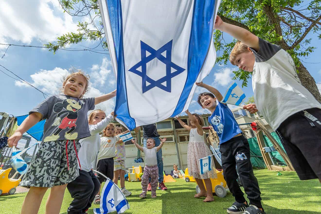Children play with Israeli flags ahead of the Jewish state's 77th Independence Day, at "Kobi kindergarden" in Moshav Yashresh, April 29, 2025. Photo by Yossi Aloni/Flash90.
