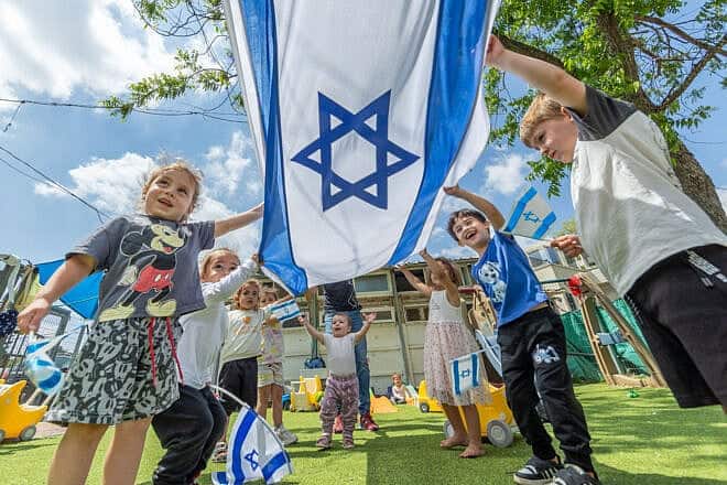 Children play with Israeli flags ahead of the Jewish state's 77th Independence Day, at "Kobi kindergarden" in Moshav Yashresh, April 29, 2025. Photo by Yossi Aloni/Flash90.