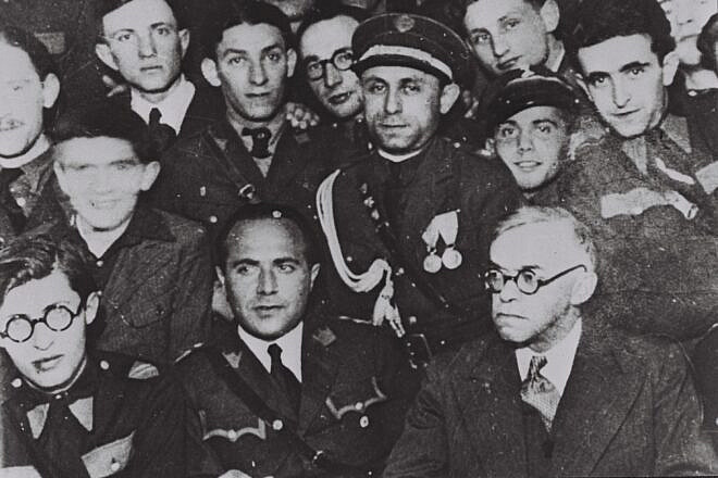 Ze’ev Jabotinsky (bottom right) at a meeting with Betar leaders in Warsaw, including (bottom, left) Menachem Begin, circa 1939. Credit: National Photo Collection of Israel/Photography Department, Government Press Office via Wikimedia Commons.