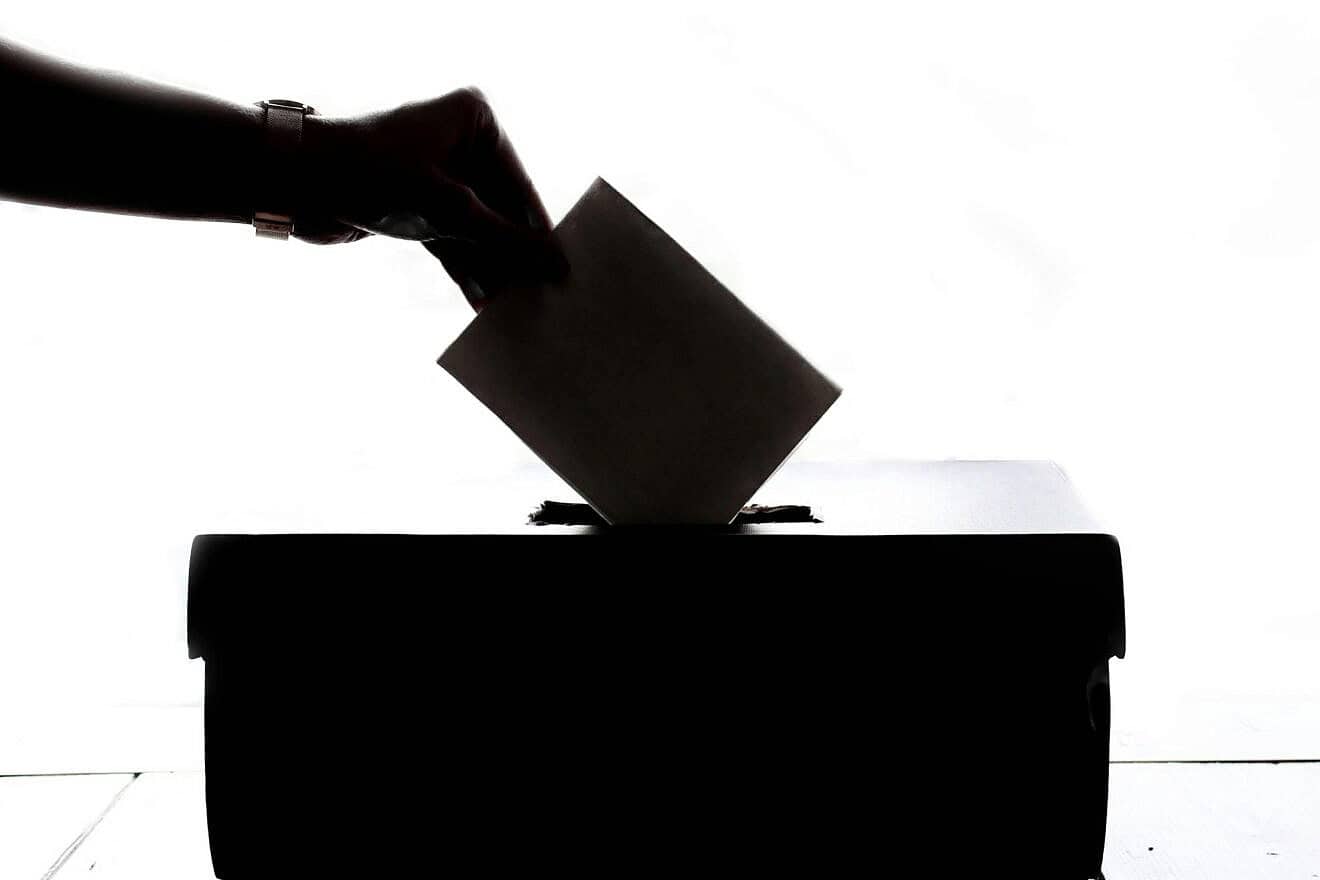 Person placing a piece of paper in a ballot box. Credit: Element5 Digital/Pexels.