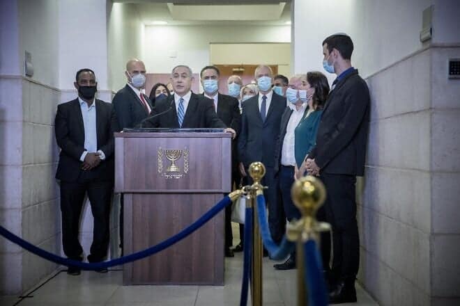 Prime Minister Benjamin Netanyahu is surrounded by Likud lawmakers as he speaks to reporters ahead of the start of his trial at the Jerusalem District Court, May 24, 2020. Photo by Yonatan Sindel/Flash90.