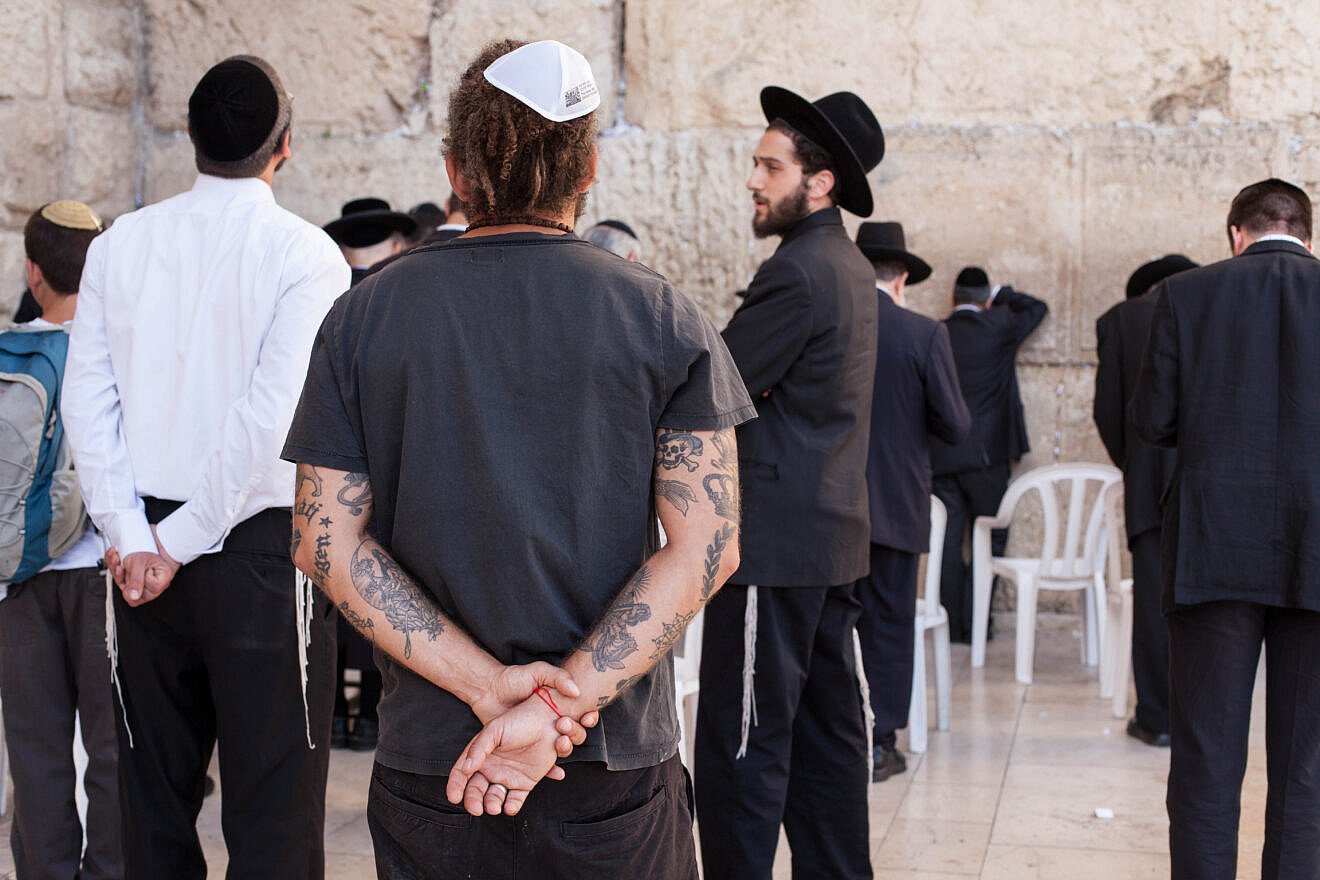 A secular man with tattoos seen next to Orthodox Jewish men at the Western Wall, on May 21, 2013. Credit: Neal Badache/Flash90.