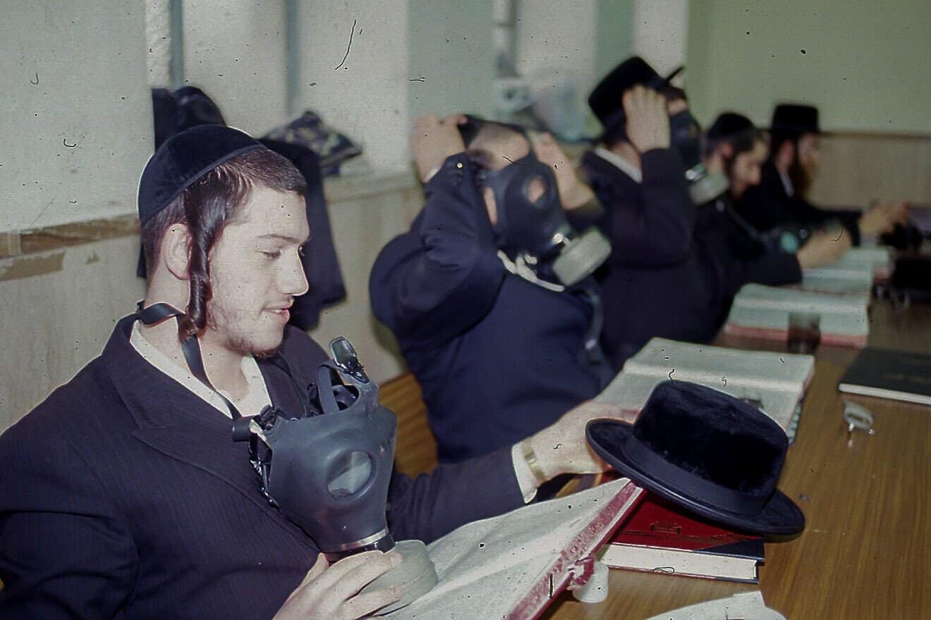 Jewish men from the Belz Chassidic dynasty study Torah with gas masks in Jerusalem during the Persian Gulf War in January 1991. Photo by Flash90.