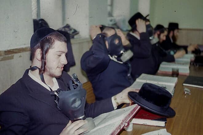 Jewish men from the Belz Chassidic dynasty study Torah with gas masks in Jerusalem during the Persian Gulf War in January 1991. Photo by Flash90.