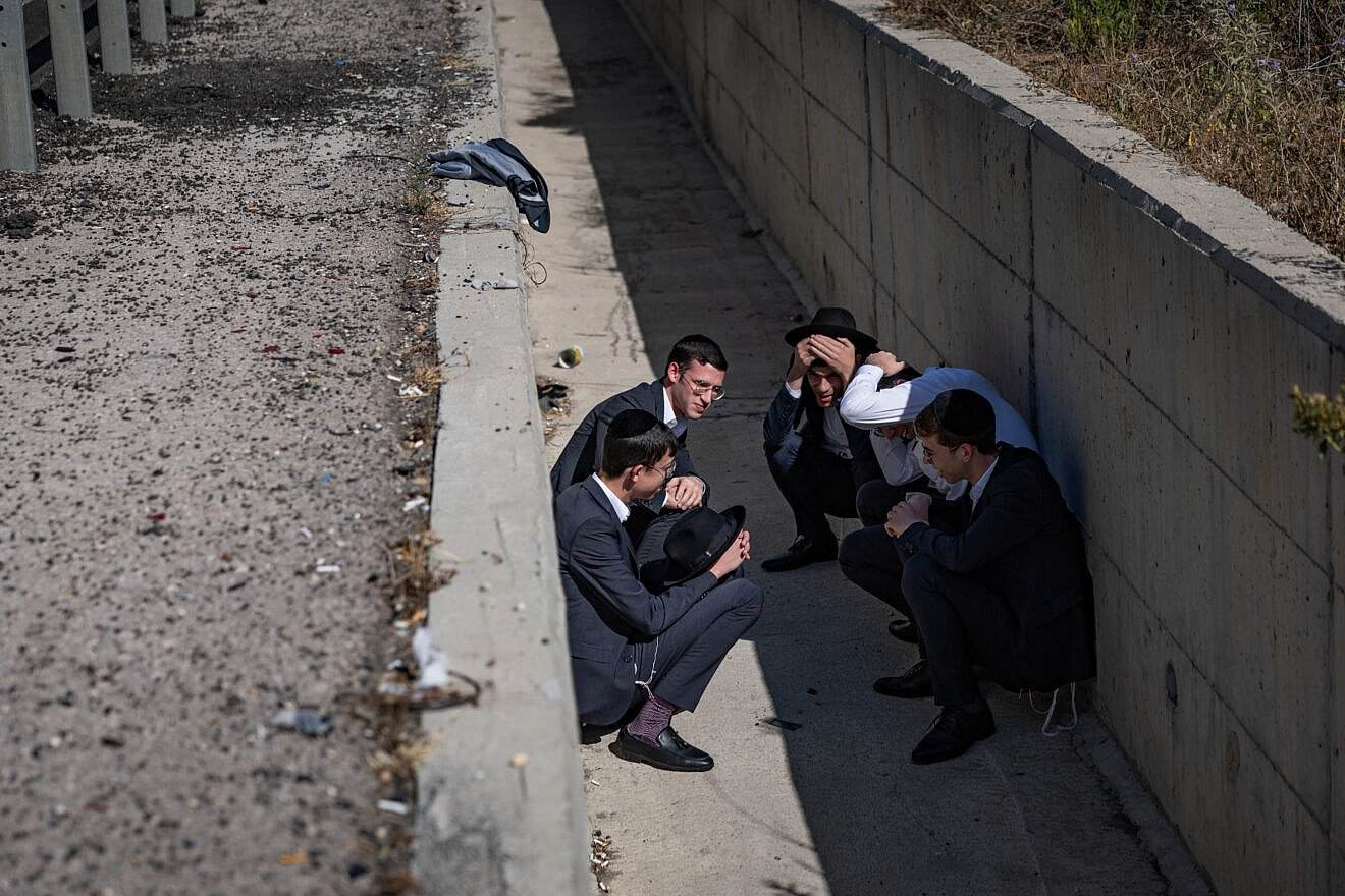 People take cover as siren warns of incoming missiles fired from Iran, on Route 1 between Tel Aviv and Jerusalem, June 15, 2025. Photo by Yonatan Sindel/Flash90.