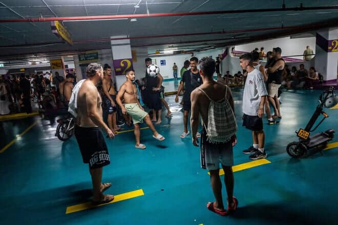 Israelis take cover as siren warns of incoming missiles fired from Iran, at a public parking lot in Tel Aviv, June 18, 2025. Photo by Chaim Goldberg/Flash90.