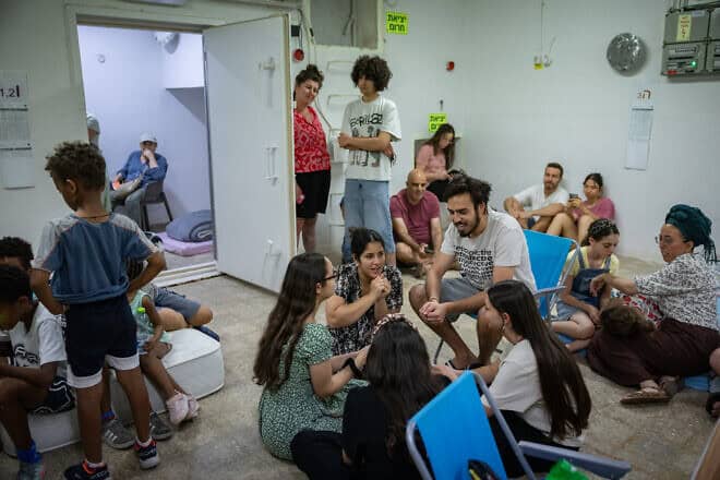 People take cover as siren warns of incoming missiles fired from Iran at a public bomb shelter in Jerusalem, June 20, 2025. Photo by Noam Revkin Fenton/Flash90.
