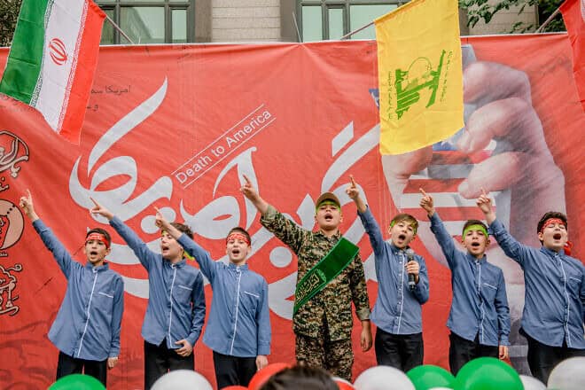 Iranian children perform on stage in front of a "Death to America" banner in Tehran, on Nov. 3, 2024. Photo by Hossein Beris/Middle East Images/AFP via Getty Images.