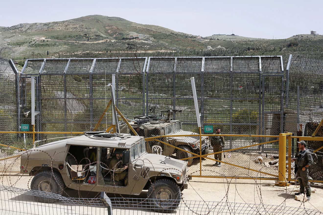 Israeli soldiers stand guard as Druze men demonstrate in solidarity with the Syrian Druze community near the border barrier in the village of Majdal Shams in the Golan Heights on April 30, 2025. Photo by Jalaa Marey/AFP via Getty Images.