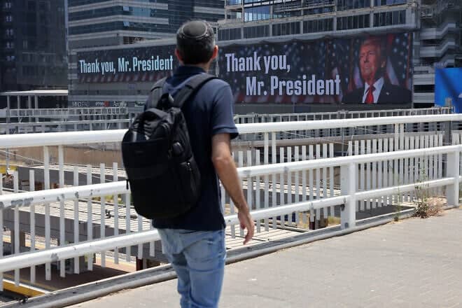 A man walks on a pedestrian bridge toward banners expressing gratitude to U.S. President Donald Trump in Tel Aviv, on June 22, 2025. Photo by Ahmad Gharabli/AFP via Getty Images.