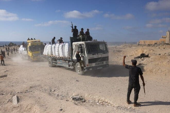 Volunteers from Palestinian families organized in committees to prevent theft, guard trucks carrying aid as they enter the Gaza Strip from the Israeli-controlled Zikim crossing, west of Beit Lahia in the north of Gaza, on June 25, 2025. Photo by Bashar TALEB/AFP via Getty Images.