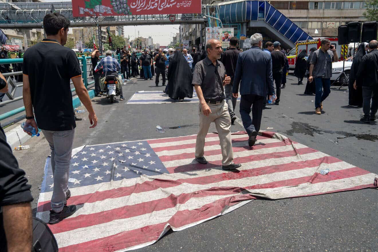 People walk on an American flag on the street as thousands of Iranians attend the funeral ceremony for approximately 60 people killed in Israeli strikes on Iran, including high-ranking military officials, nuclear scientists, and civilians, during a state funeral service in Enqelab Square in Tehran, on June 28, 2025. Photo by Majid Saeedi/Getty Images.