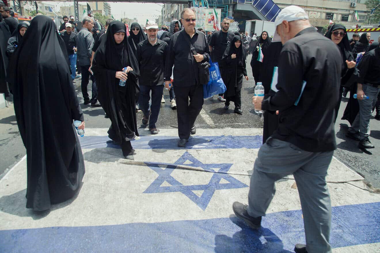 People walk over an Israeli flag in the state funeral procession of Iranian military commanders and scientists killed in Israeli strikes on Azadi (Freedom) Street in Tehran, on June 28, 2025. Photo by AFSHIN/Middle East Images/AFP via Getty Images.